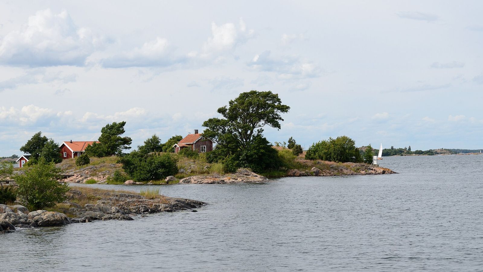 Liten ö med röda stugor och tallar i Östergötlands skärgård