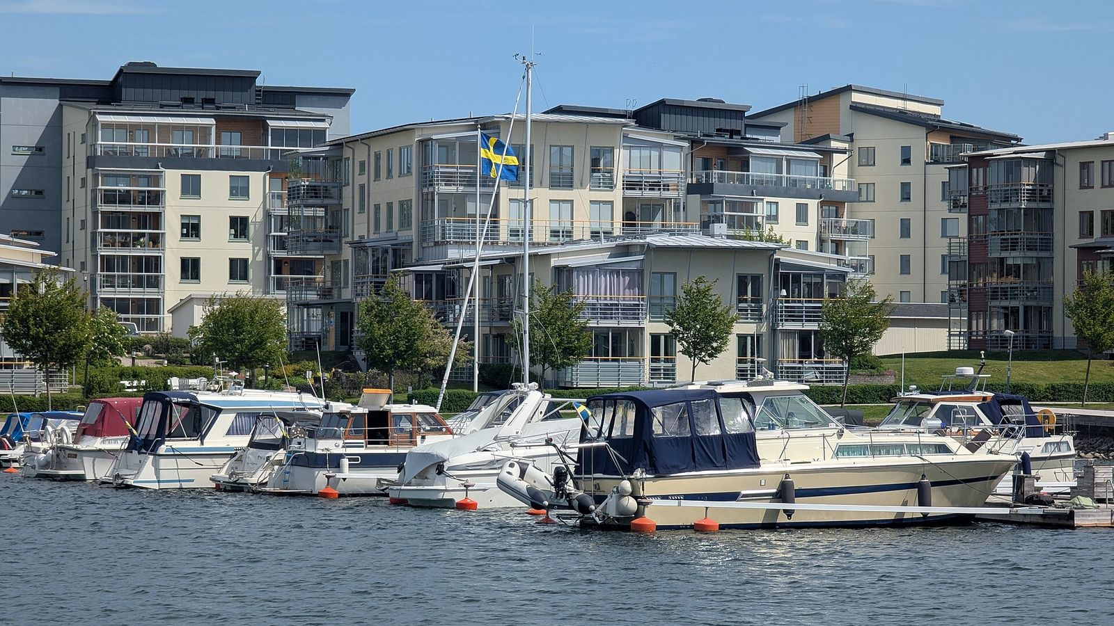 Motorbåtar och segelbåtar vid flytbryggorna i Västervik med bostadshus längs kajen