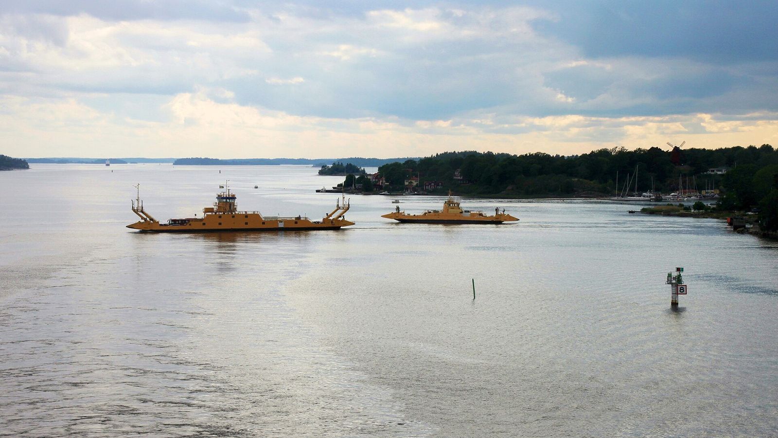 Furusundsleden med ett passerande fartyg och gästhamnens bryggor vid stranden