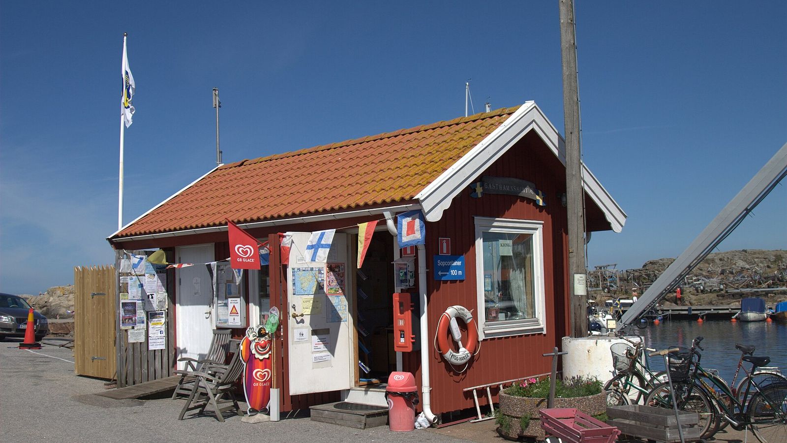 Litet rödmålat hamnkontor med livboj på väggen vid kajen i en västkusthamn
