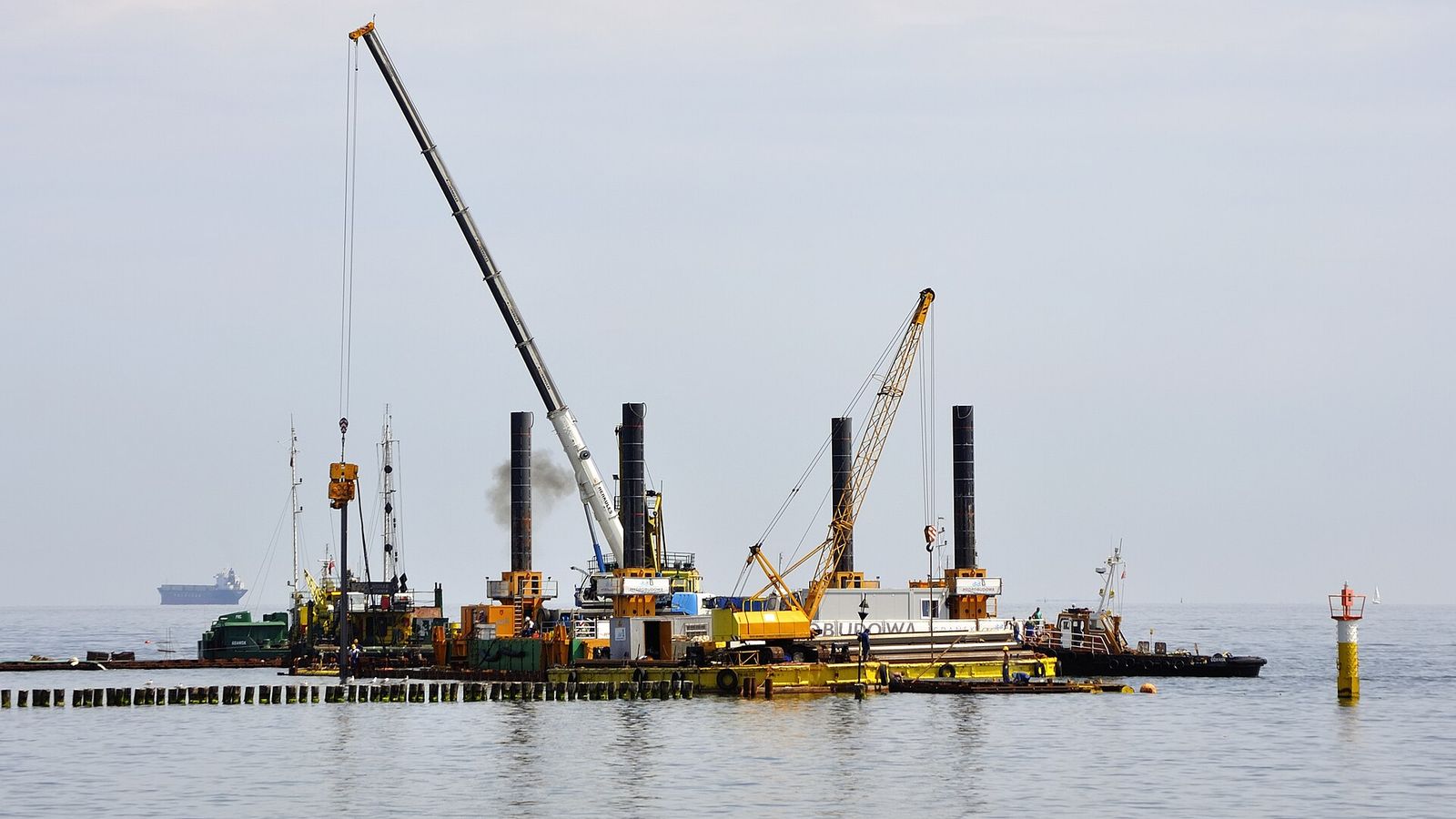 Arbetspråmar med kranar bygger marinan vid piren i Sopot