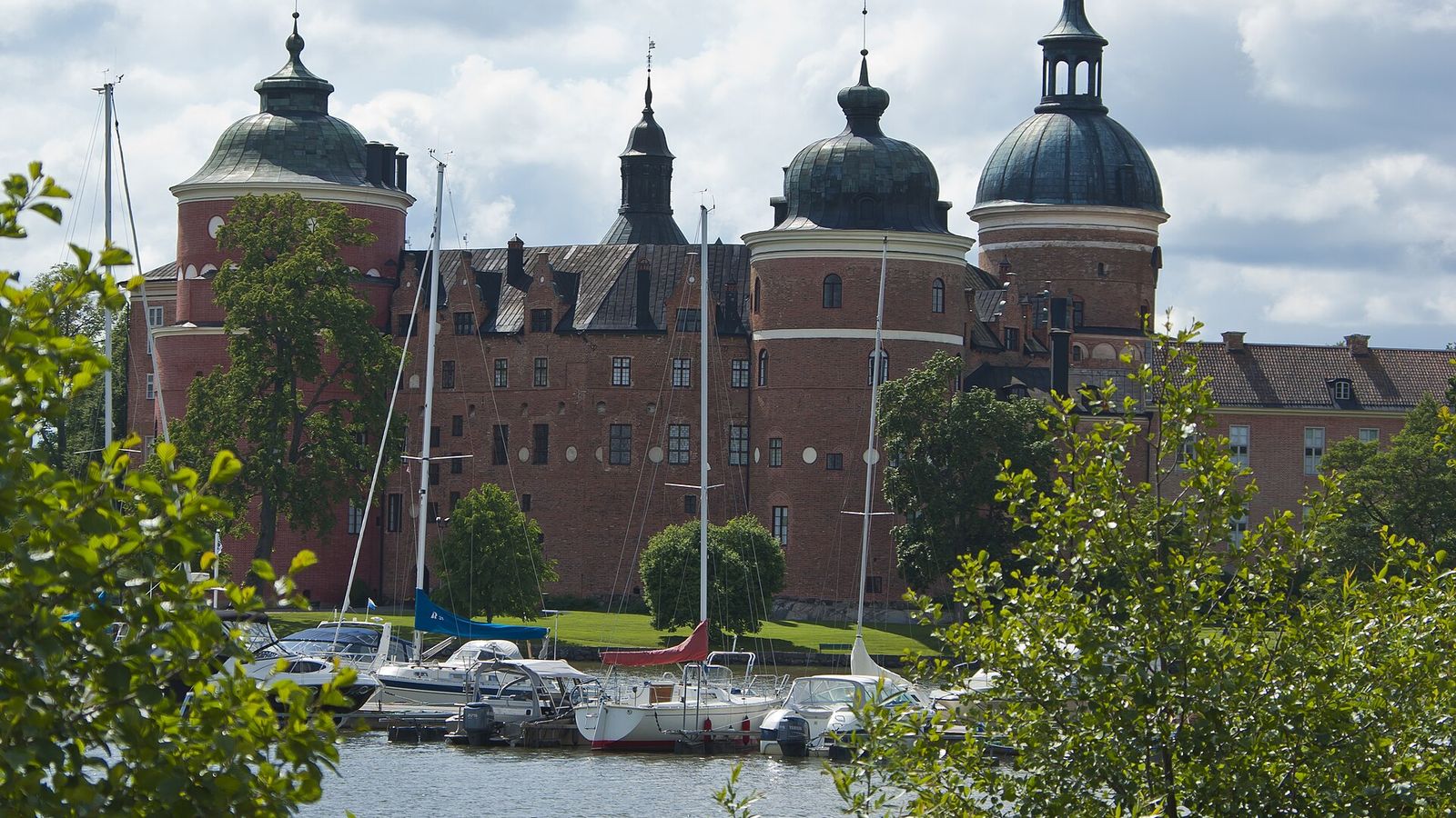 Gripsholms slott speglar sig i viken vid Mariefred med gästhamnens bryggor i förgrunden