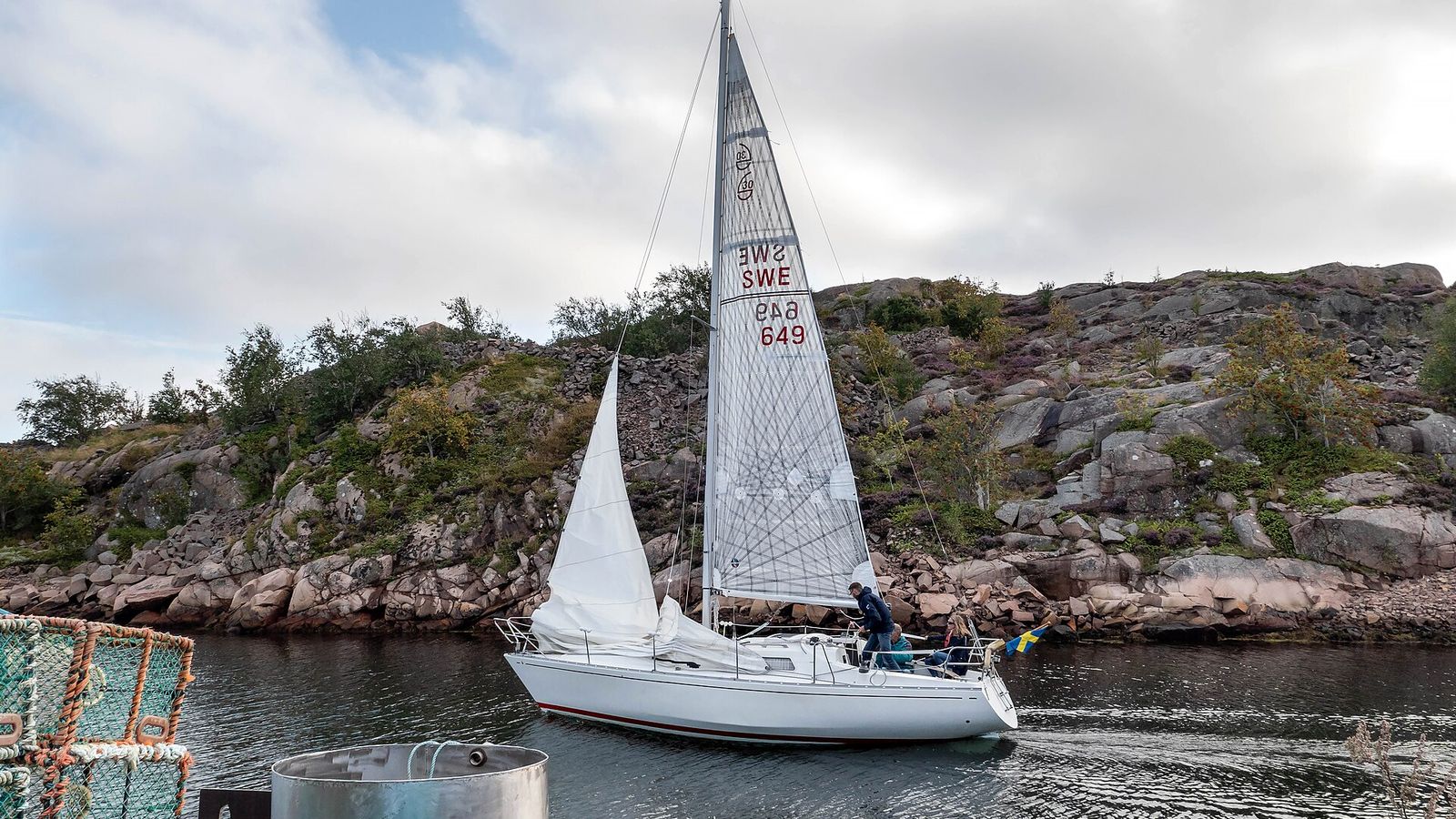 Segelbåt på väg hem för segel längs klipporna i skärgården